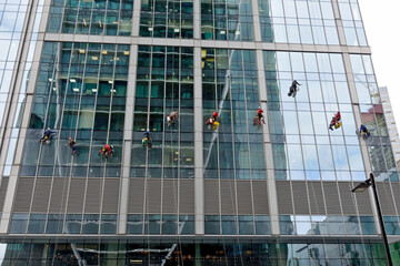 Industrial climber washes glass on the facade of a skyscraper. Industrial mountaineering, high-rise facade cleaning services