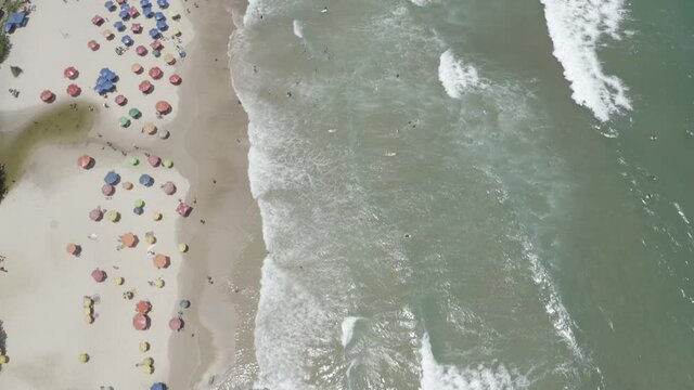 Vue a&eacute;rienne avant des vagues de l'oc&eacute;an, des parasols, des palmiers verts sur la plage, des surfer.. &Eacute;t&eacute; &agrave; Praia Itacare Bahia, Br&eacute;sil. Paysage tropical avec personnes, parasols, sable, eau