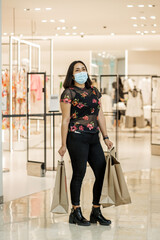 Obraz na płótnie Canvas Mujer joven con cubre bocas de compras en centro comercial 