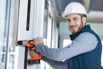 skilled professional using electric drill on the window