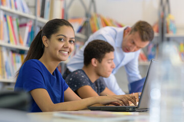 young students doing homework with laptop in the library