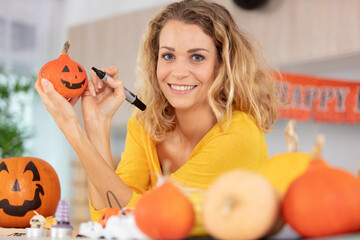 beautiful young woman decorating pumpkin and smiling