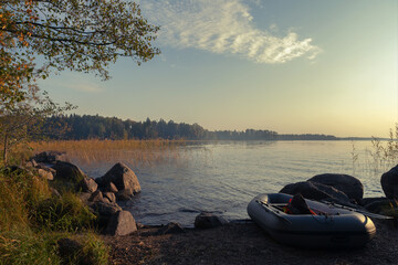 inflatable boat with a fishing rod and a life jacket on the background of a foggy lake