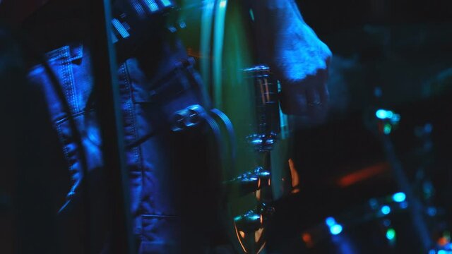 The guitarist slowly plays his guitar in the spotlight. Hands of a guitarist playing the guitar. Low key