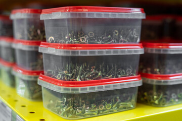 Several stacks of plastic containers with nails on yellow shelf