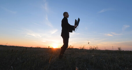 Silhouette of young male kung fu fighter practising alone in the fields during sunset	