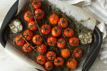 baked tomatoes with garlic and thyme on a baking sheet close-up