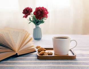 Still life with a cup of coffee and a book. The atmosphere of a cozy morning. Breakfast at home or in a cafe near the window