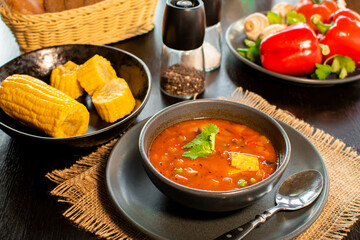 Mexican tomato, bean, bell pepper soup and corn in the dark bowl.