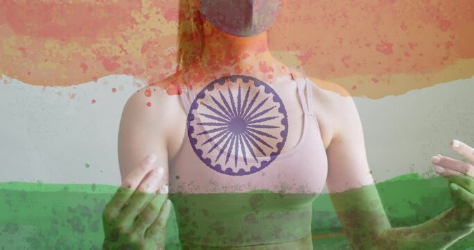 Animation of woman wearing face mask practicing yoga over indian flag