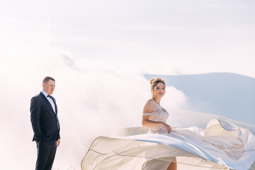 loving couple of newlyweds in white dress and suit in the field. The woman is spinning, dancing, having fun.