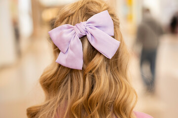 hairstyle on long blond curly hair: lilac bow on the back of the head, back view, close-up