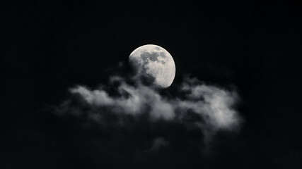Naklejka na ściany i meble The moon rising above a lone cloud.