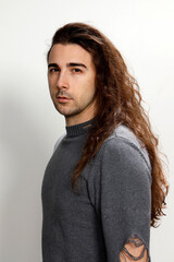 Fototapeta na wymiar Attractive young guy with very long curly hair is posing in studio. Style, trends, fashion concept.