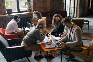 Obraz premium Business people in protective masks working by tables in office