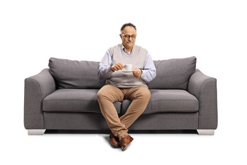 Mature man sitting on a sofa and drinking a cup of coffee