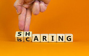 Sharing is caring symbol. Businessman turns wooden cubes with words 'sharing is caring'. Beautiful orange table, orange background. Business, sharing is caring concept. Copy space.