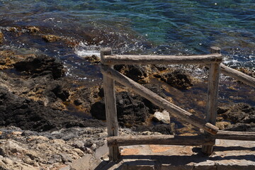 Szary drewniany płotek na tle kamienie i morza, Kreta, Grecja