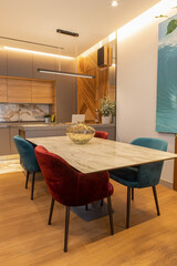 Stylish modern kitchen interior, studio. Large table with velvet chairs. Zone in living room, dining room, designer wood veneer panel on wall. Concept minimal fashionable interior, natural materials