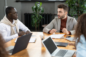 Two intercultural businessmen consulting or brainstorming at meeting