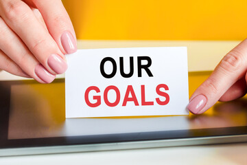woman holds a piece of paper with the text our goals, concept