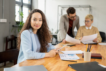 Obraz premium Successful female manager working with papers and online data against two colleagues