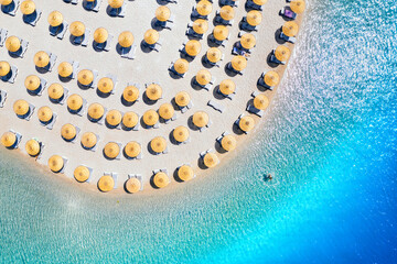 Aerial view of sea, empty sandy beach with sunbeds and umbrellas at sunny day in summer. Blue lagoon in Oludeniz, Turkey. Tropical landscape with clear turquoise water, deck chairs. Travel and leisure