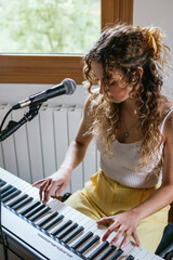 Young woman playing piano at home studio - obrazy, fototapety, plakaty