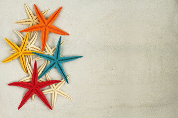 Fototapeta na wymiar Colorful painted Starfishes on light gray sand. Top down view. Closeup