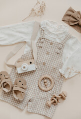 Flat lay Baby natural material accessories concept. Wooden toys, clothes and shoes on beige background. Bohemian baby fashion.