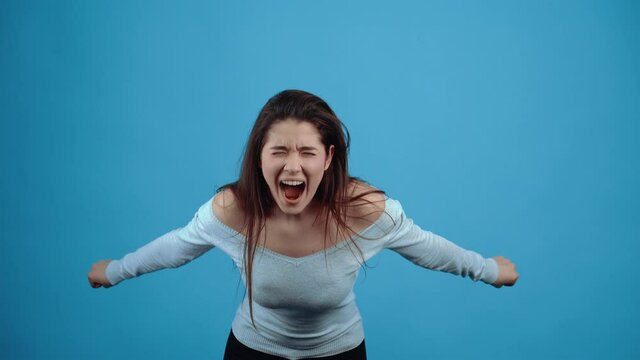 The angry young woman, overloaded with the problem, strives with all her might to feel better. Asian with dark hair, dressed in a blue blouse, isolated on a dark blue background in the studio. The