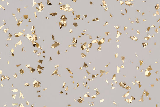 Gold confetti sparkles on grey background, golden chic holiday backdrop.