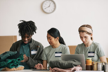 Young people organizing boxes while volunteering at charity and donations event - Powered by Adobe