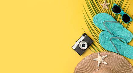 sun hat, flip flops, sunglasses, camera, palm leaf and starfish on yellow background with copy space. summer background with beach accessories. summer background with beach accessories