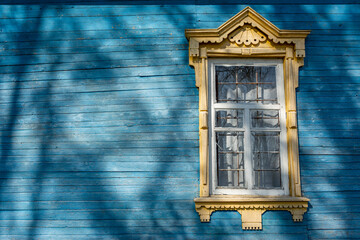 Old rural house wall, paneled with blue wood and a window