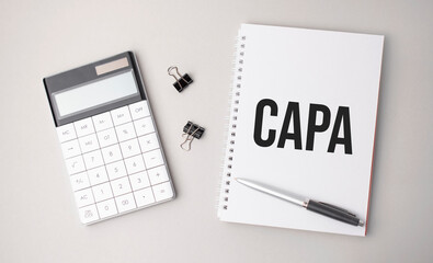 The word capa a is written on a white background next to a pen ,calculator and reports. Business concept