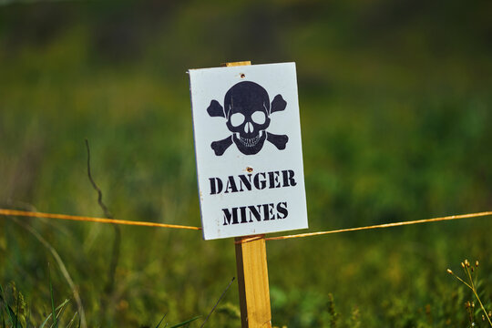 Close-up of a sign with a skull warning of danger in a minefield