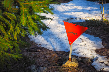 Red metal triangle sign in the forest bewaring of mines - 435510312