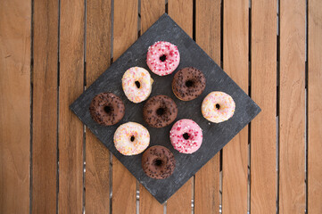 rhombus black dish with nine donuts on wooden table background