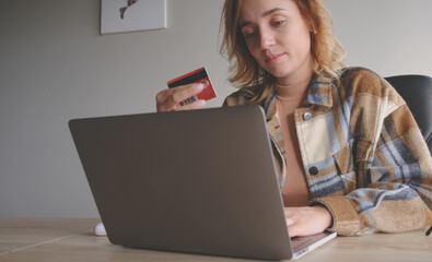 Buying in online shop. Woman using laptop and buying a use credit card.