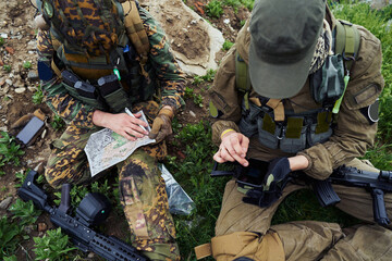 Airsoft players sit on the ground and examine the map