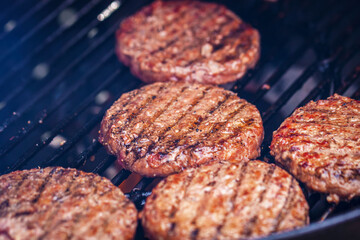 Beef burgers for hamburger on metal barbecue grill close-up, BBQ day