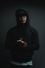 cool rapper with black hoodie and cap clapping his hands in front of grey background