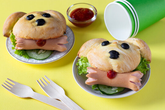 Sandwiches in the shape of a dog with a sausage on yellow background. Cooking idea for kids. Closeup