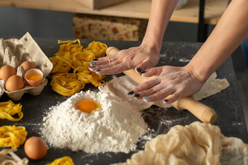 Closeup of process of making homemade pasta. Woman's hands roll out the dough. Woman preparing dough for pasta 