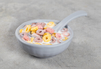 Healthy breakfast, corn and oatmeal fruit berry rings with milk in a bowl on a light gray background