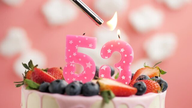 Birthday cake candle number 53. Candle and cake on pink background and fire by lighter. Close-up and slow motion