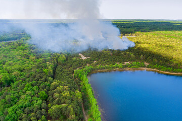 Fototapeta na wymiar Aerial panorama view of smoke in the forest fire burning trees near pond