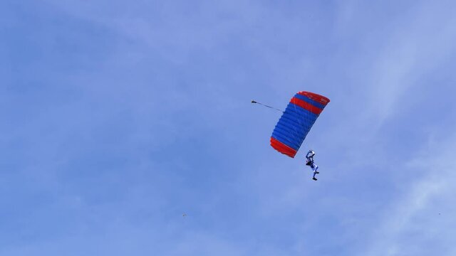 Parachutist Flies on a Paraglider in Blue Sky and Lands on Green Grass. Single, Self jump. Paragliding. Skydiving in clear weather. Extreme sport. 4K. Slow motion.