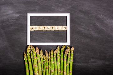 Fresh asparagus near a white frame on a black chalk board with a place for your text.